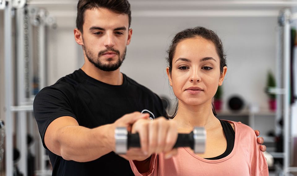 personal trainer help woman raise weight